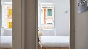 Ein Schlafzimmer mit einem Bett, einem Nachttisch, einer Lampe und einem Fenster mit Rollläden.