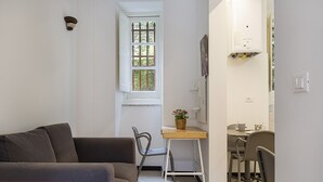 A compact living space with a sofa, a small dining table, and a chair, indicating a smart working setup.