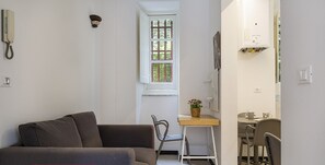 A compact living space with a sofa, a small dining table, and a chair, indicating a smart working setup.