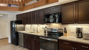 A modern kitchen with dark wooden cabinets, stainless steel appliances, and a granite countertop.