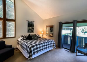 Une chambre à coucher avec un lit, une chaise, une lampe, un miroir et une vue sur l’extérieur.