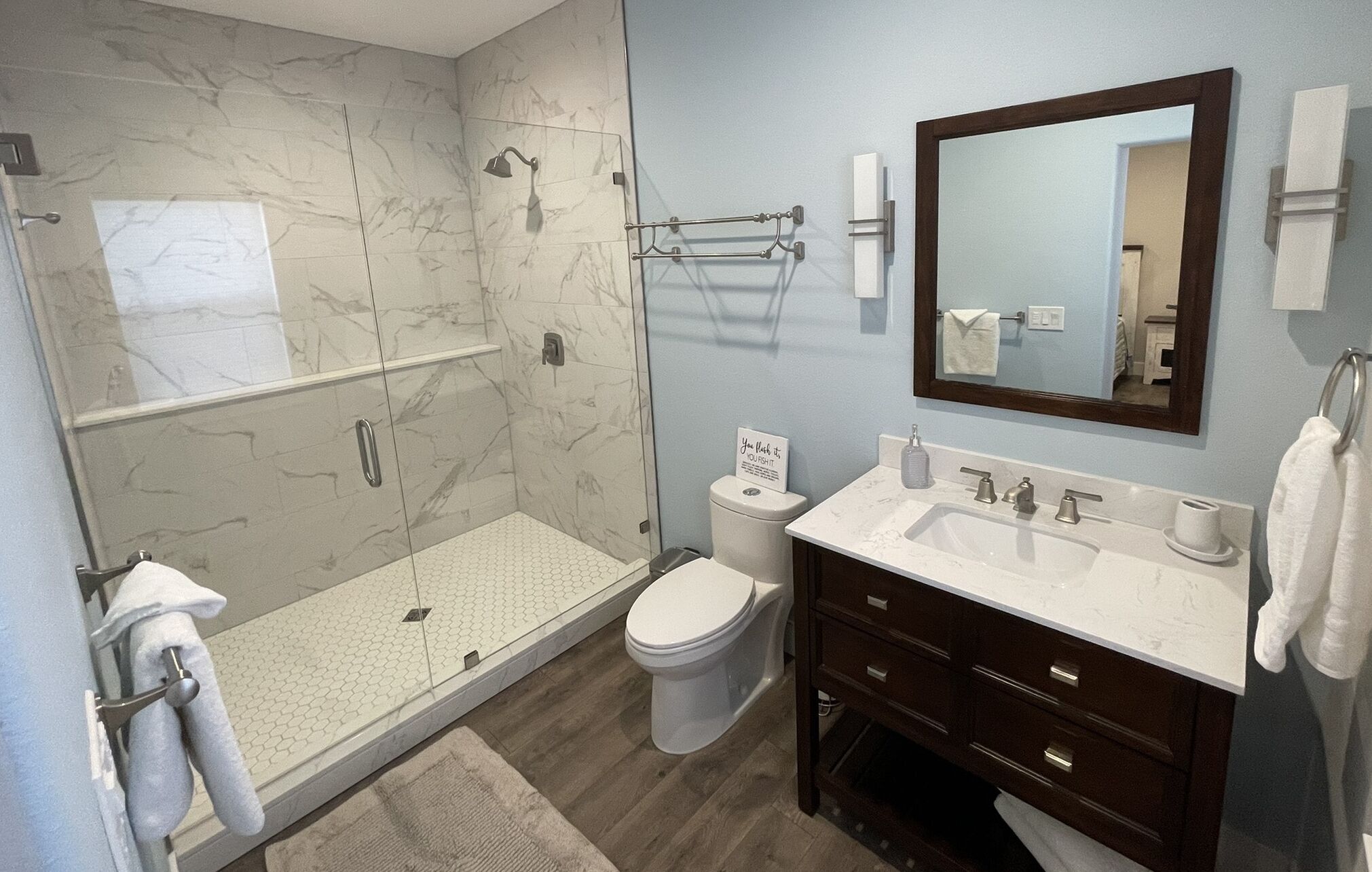 Une salle de bain moderne avec une douche à parois de verre, des toilettes, un lavabo avec un miroir et un porte-serviettes.