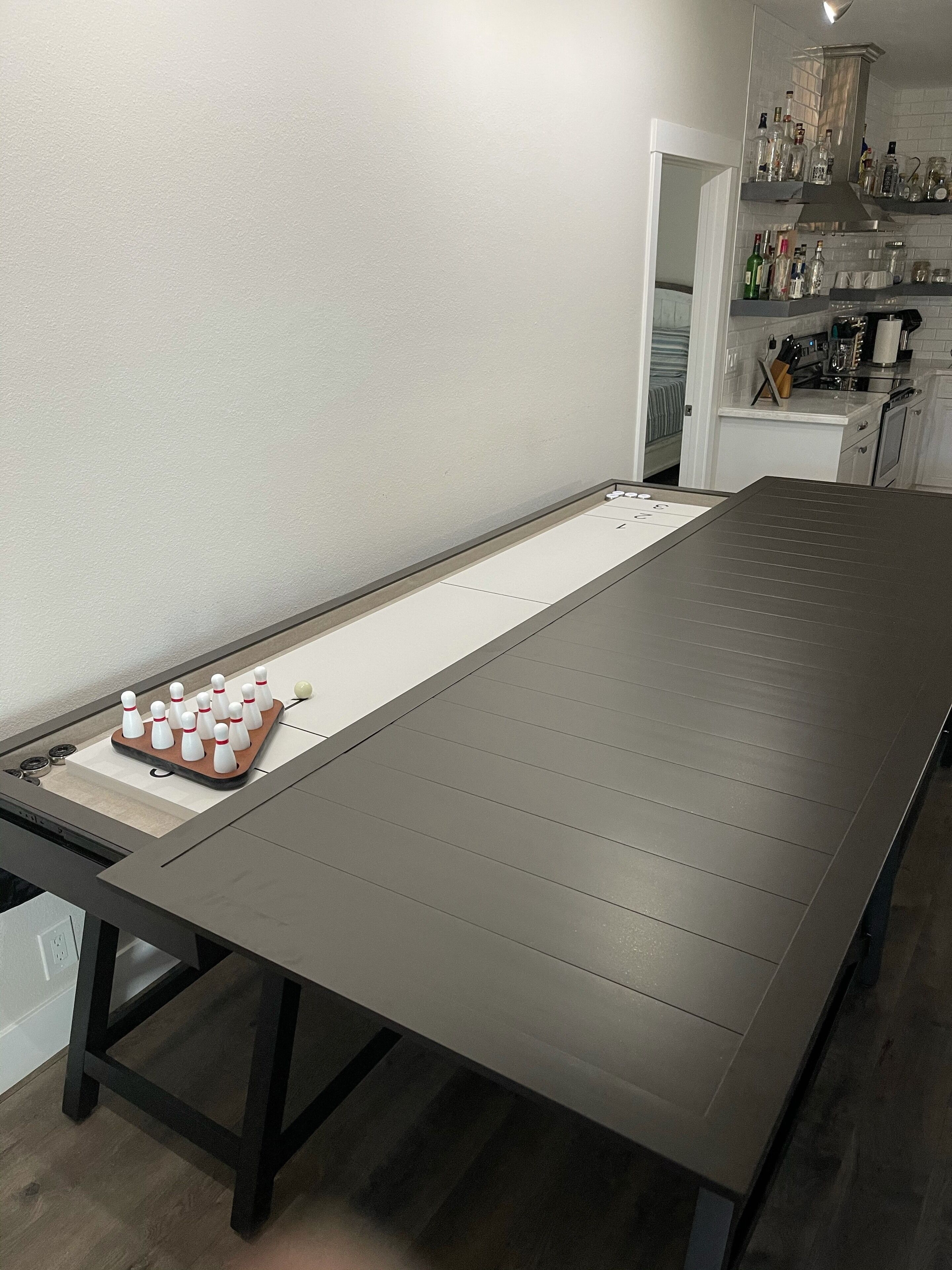 Une longue table étroite, recouverte d’une nappe blanche, sur laquelle sont disposées des quilles.