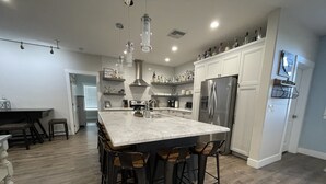 A modern kitchen with a large island, bar stools, stainless steel appliances, and pendant lighting. - Area 51 Annex - Alien Lake Escape -  - Minutes from the River / Casinos / Lake! (Bullhead City)