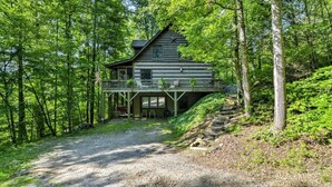 A cabin with a porch, surrounded by trees.