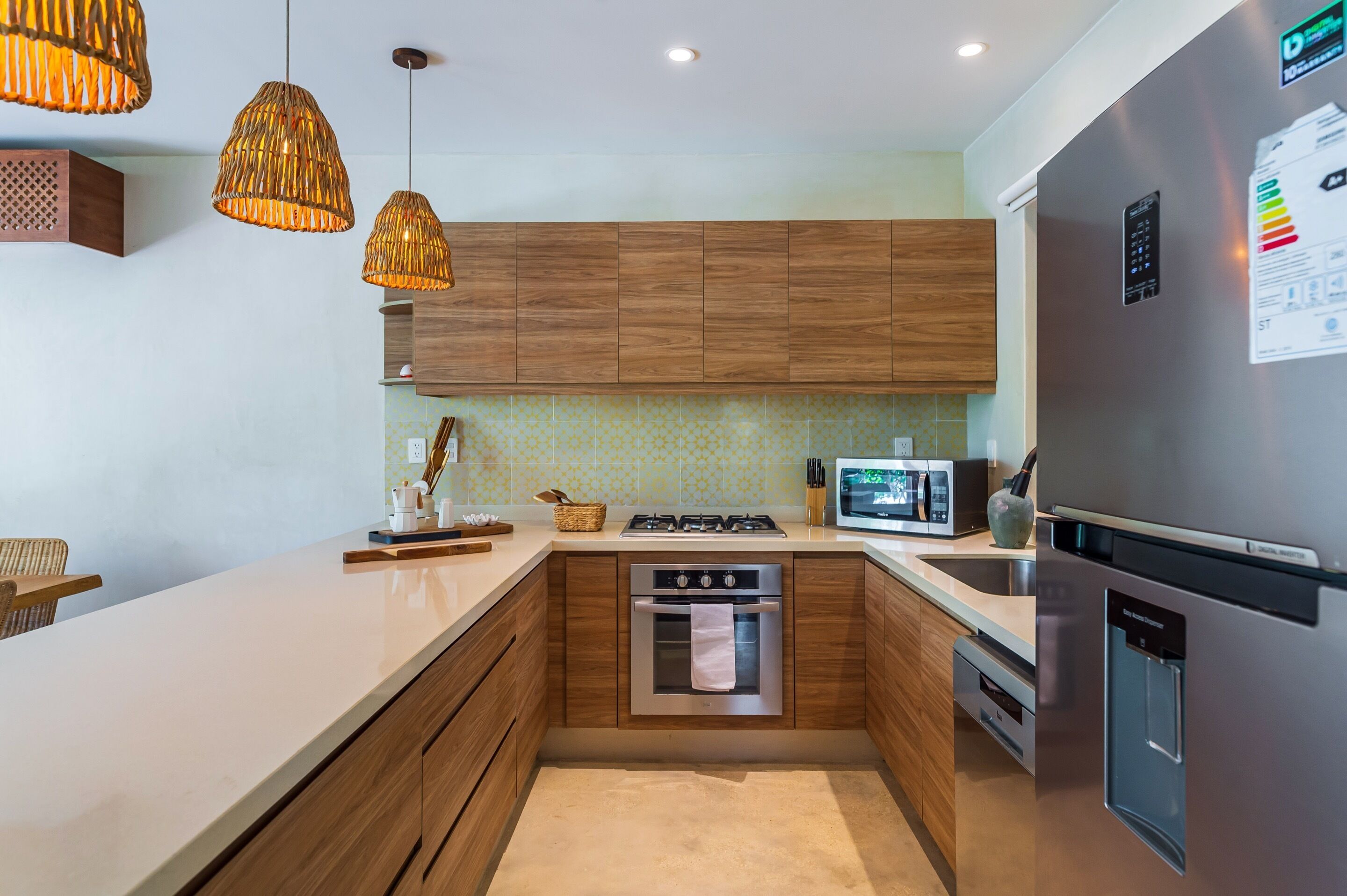 A modern kitchen with wooden cabinets, a stainless steel refrigerator, a built-in oven, and a microwave.