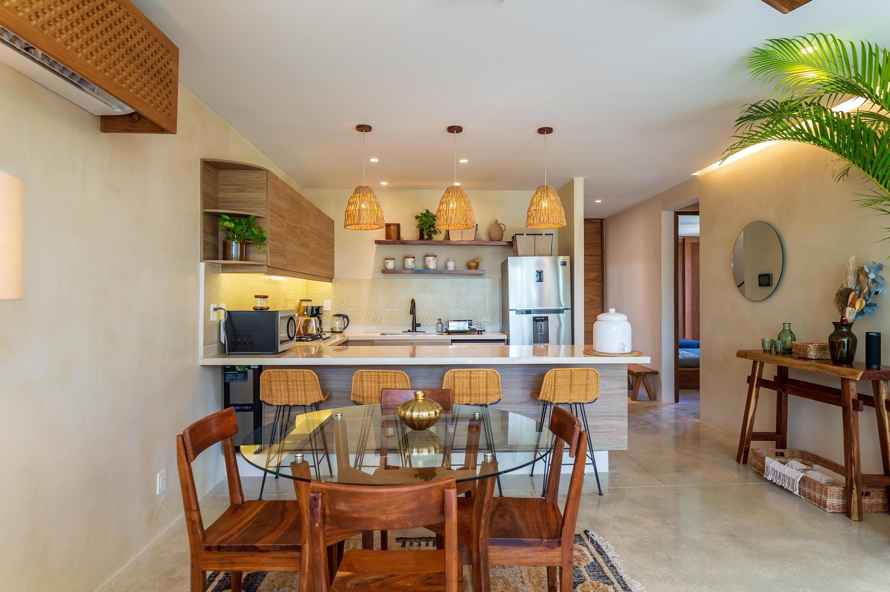 Una cocina moderna con una isla central, sillas de madera y luces colgantes.