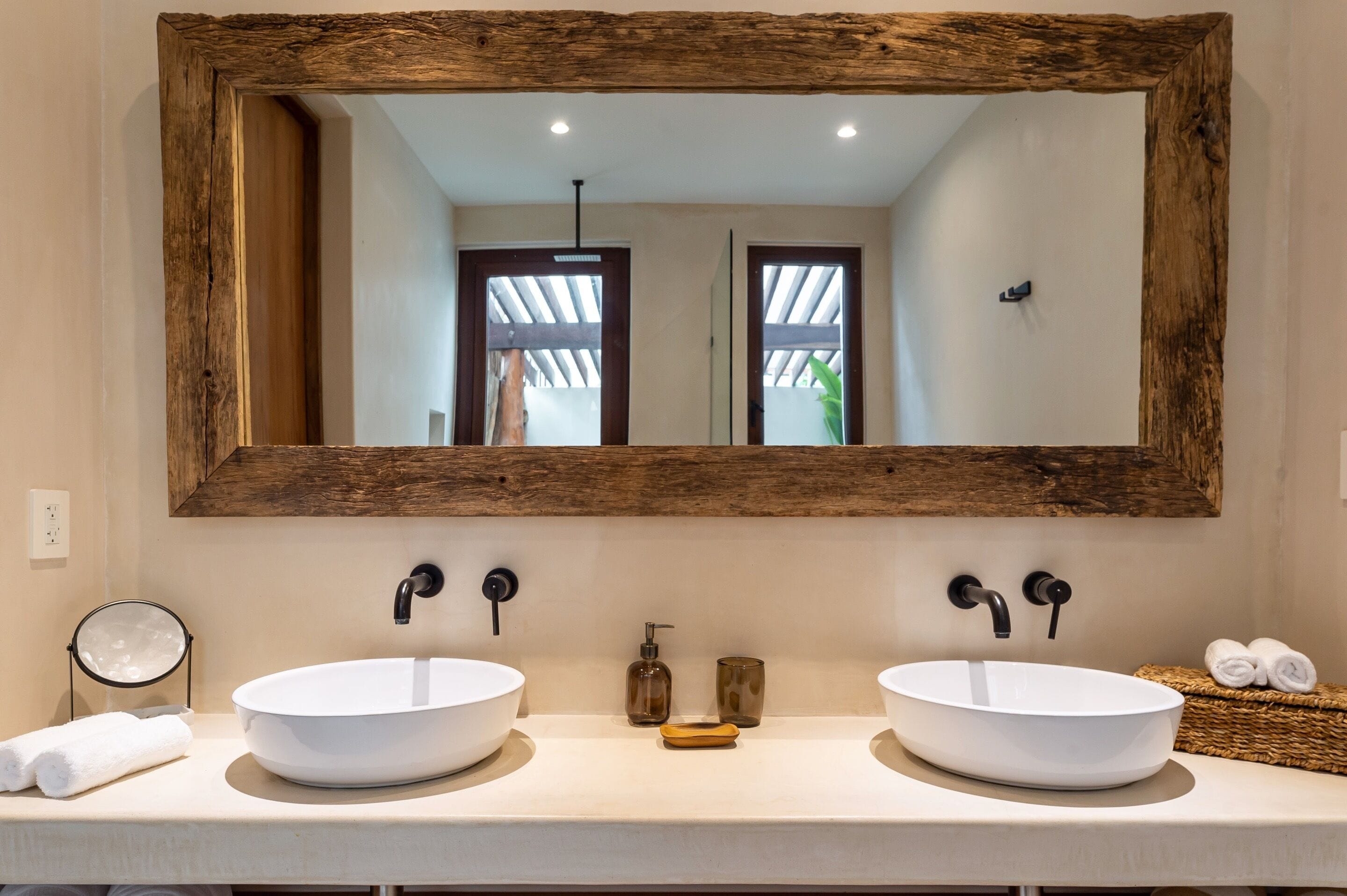 Une salle de bain avec deux lavabos blancs, un miroir encadré en bois et un porte-serviettes avec des serviettes.