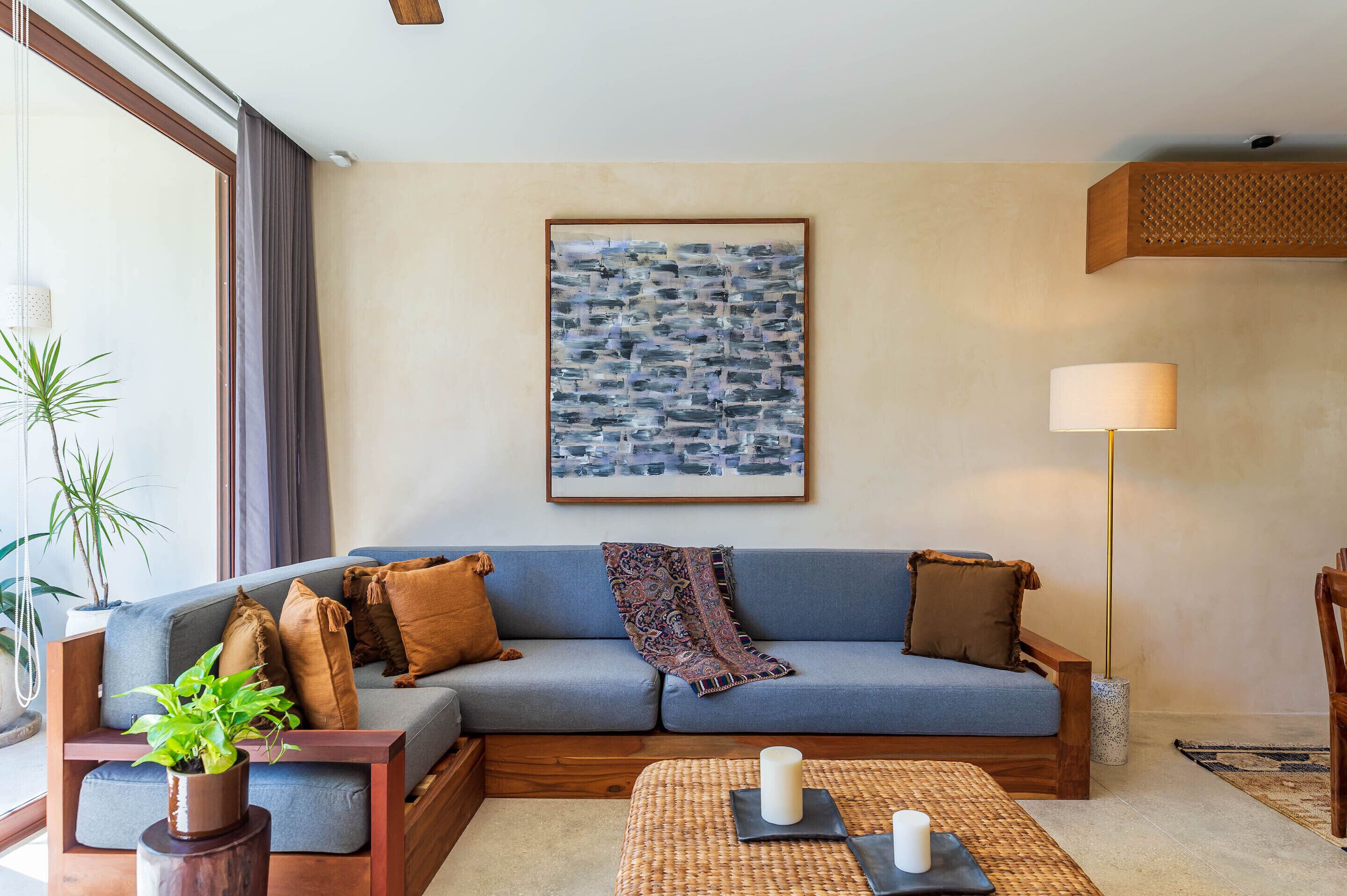 Una sala de estar moderna con un sofá azul, un cuadro abstracto grande, una lámpara de pie y una planta en maceta.