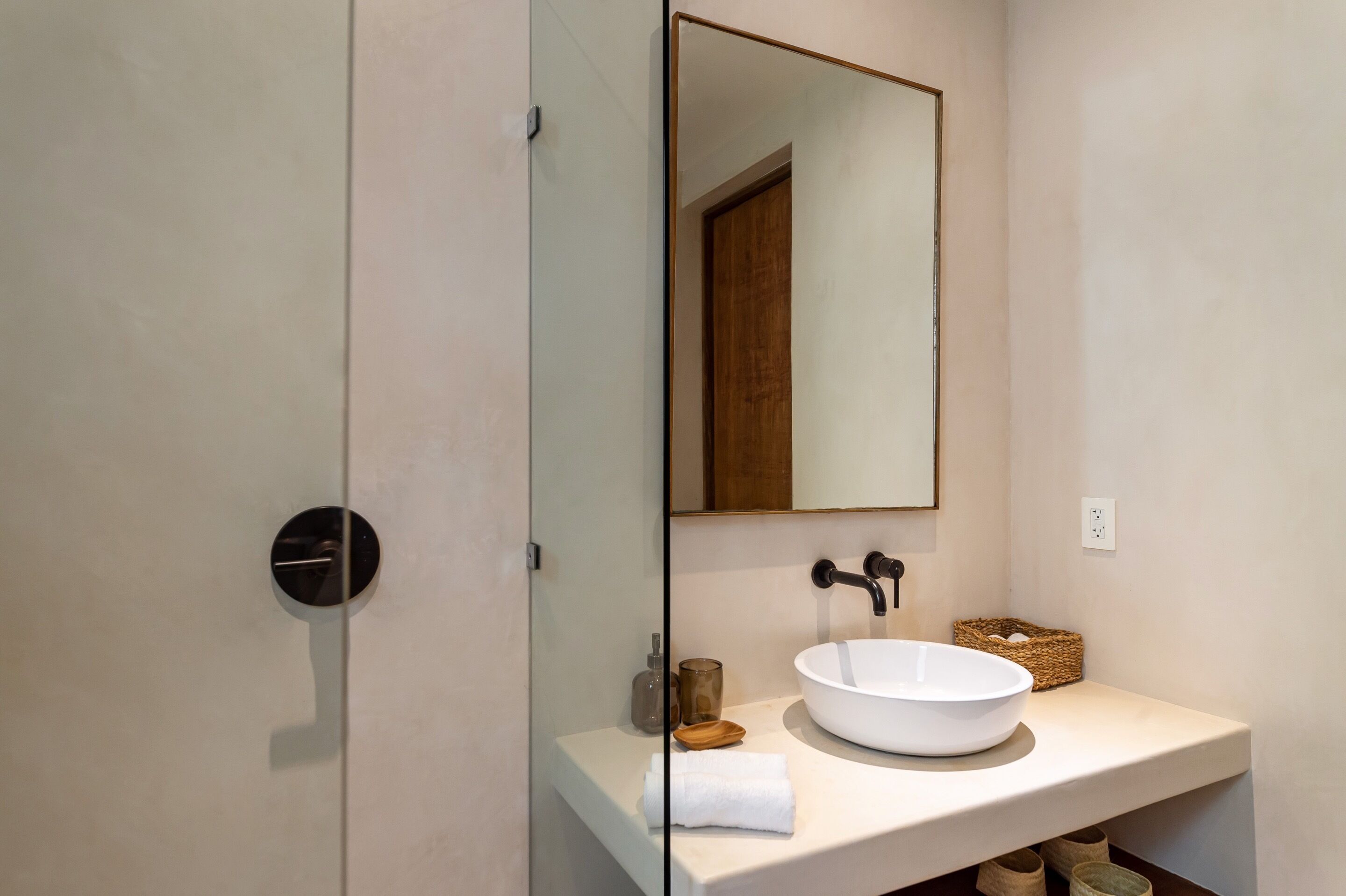 A modern bathroom with a round white sink, a mirror, and a towel on the counter.