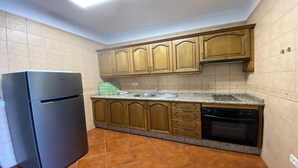 A compact kitchen with wooden cabinets, a black refrigerator, a sink, and a dishwasher. - Yuremar La Puntilla Apt  3 (Valle Gran Rey)