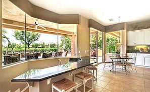 Una cocina amplia con una isla grande, taburetes de bar y un comedor con sillas.