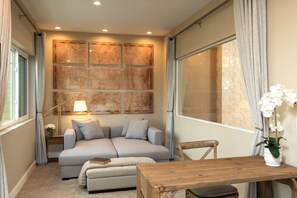 Relax in this inviting room with a sofa, table, and chair, surrounded by elegant panels and a beautiful orchid.