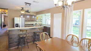 A kitchen with a central island, bar stools, a dining table with chairs, and a chandelier. - Whippoorwill Hill: Easy Access Guadalupe Riverfront, Great Patios, Mins to Whitewater Amphitheater (Canyon Lake)