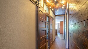 A hallway with wooden doors and a ceiling light fixture. - Whippoorwill Hill: Easy Access Guadalupe Riverfront, Great Patios, Mins to Whitewater Amphitheater (Canyon Lake)