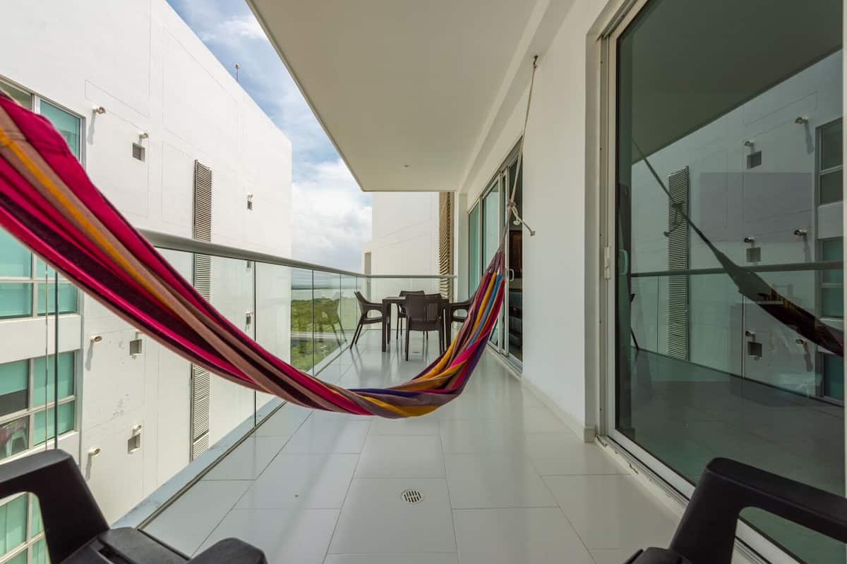 A balcony with a hammock, glass doors, and a view of the city.