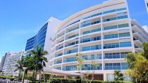 Ein modernes Hotel mit geschwungener Fassade, mehreren Balkonen und blauem Himmel.