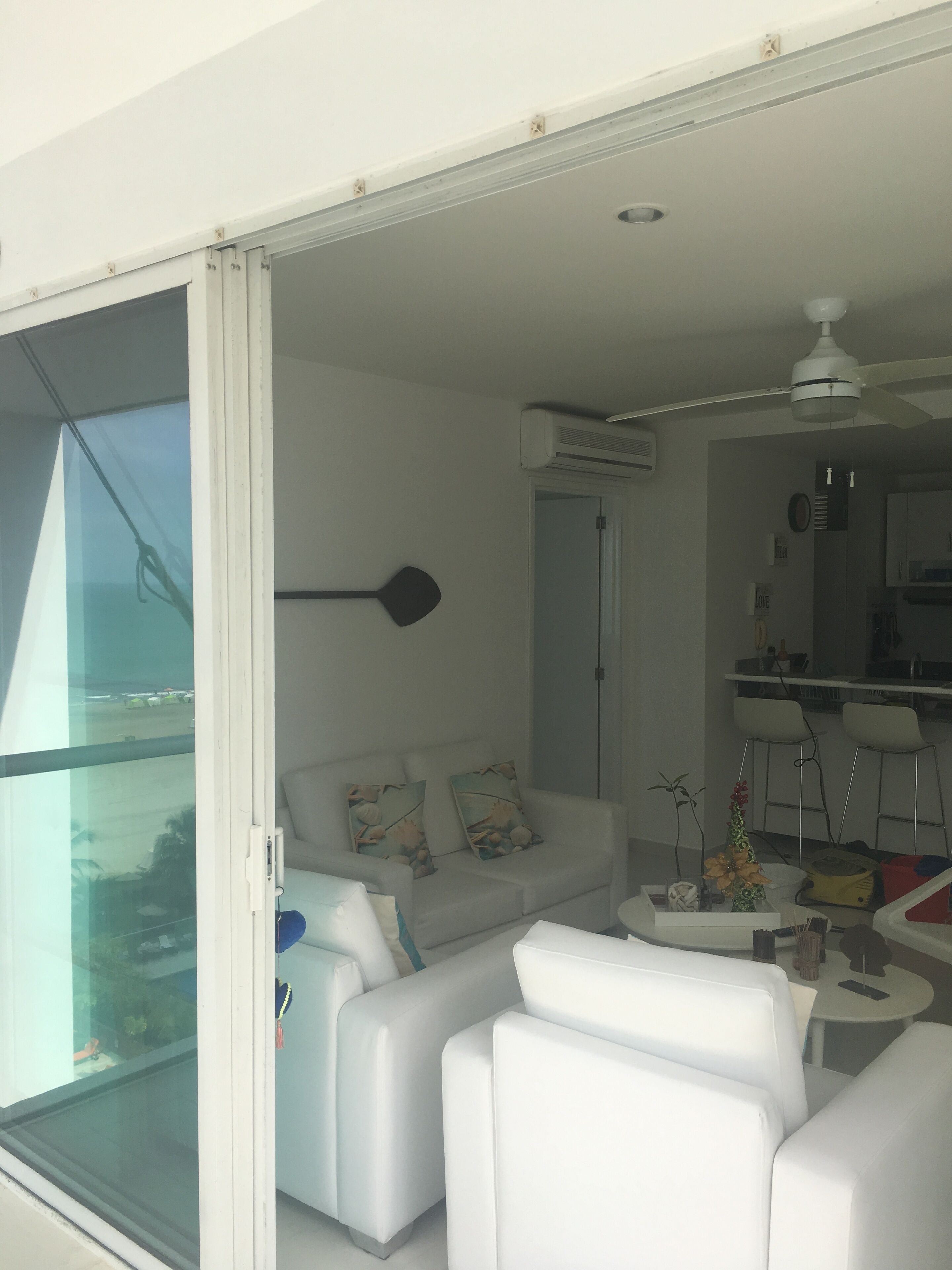 Una sala de estar moderna con un sofá blanco, una mesa de centro y vistas a través de un ventanal.