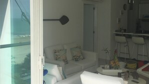 Ein modernes Wohnzimmer mit einem weißen Sofa, einem Couchtisch und Blick durch eine Glastür.