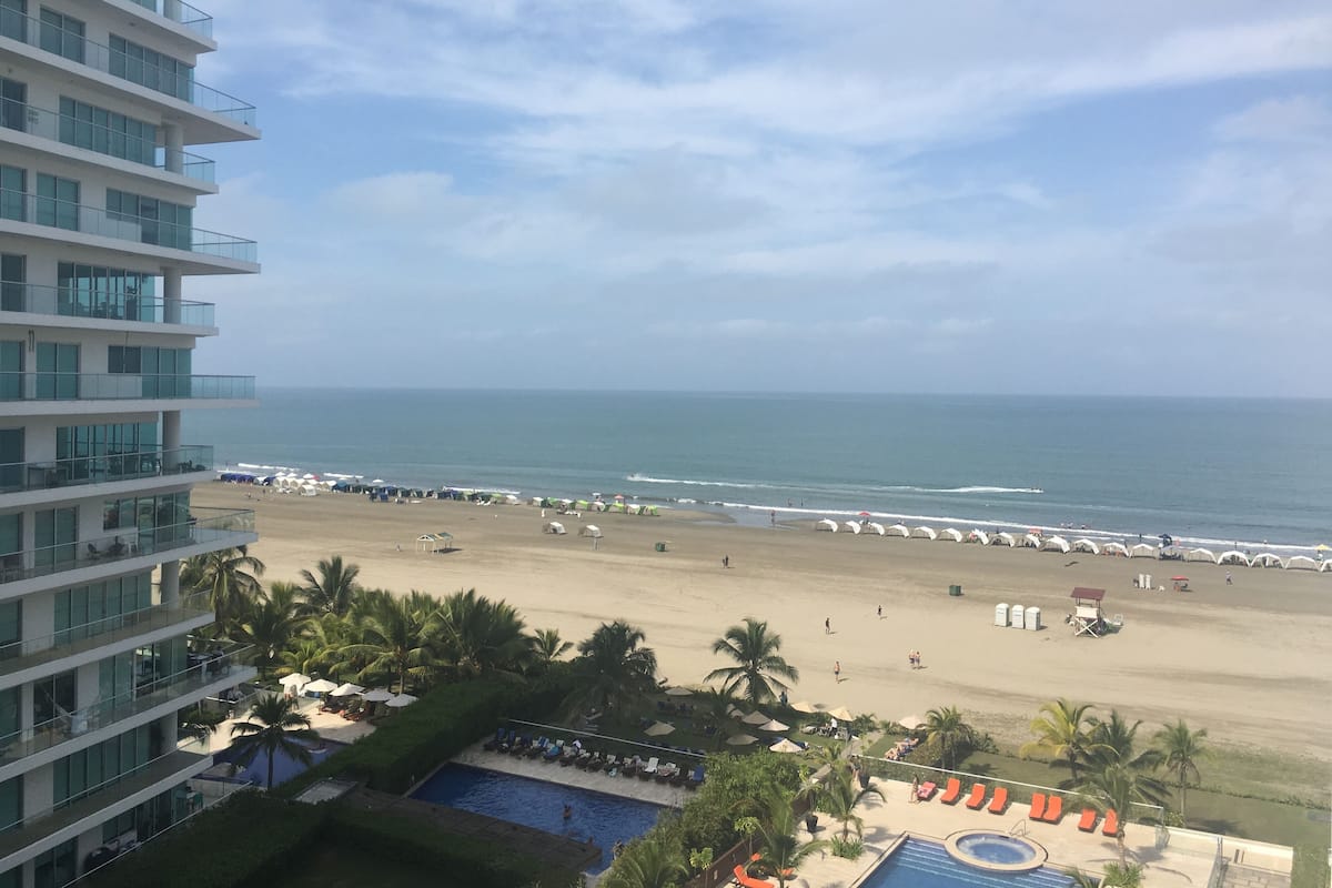 A hotel with a pool, beach, and ocean view.