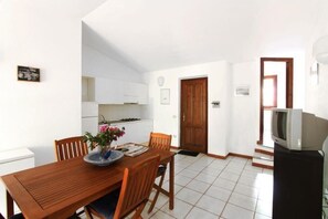 Cozy room with a dining table for two, TV, and a vase of flowers.