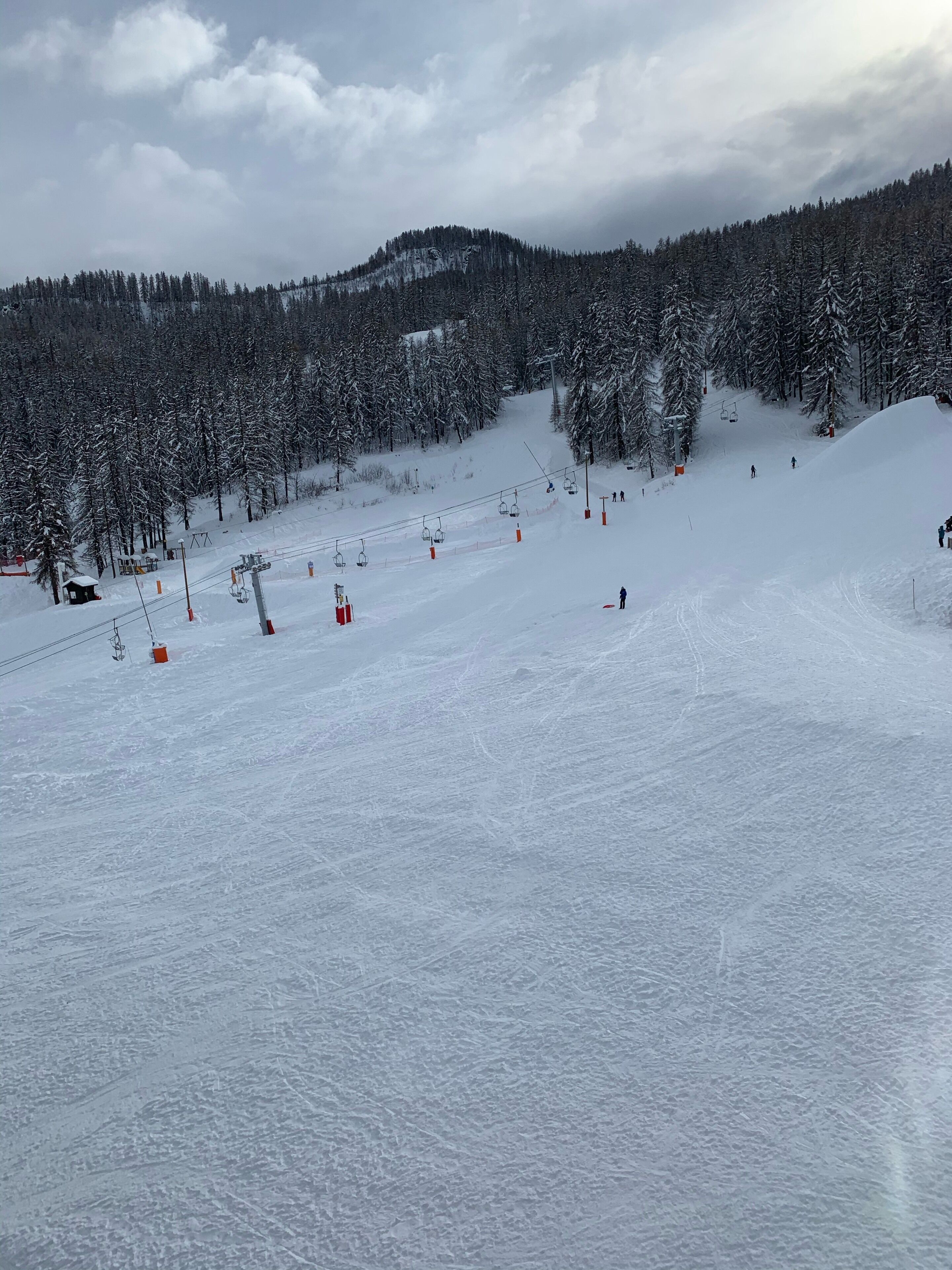 A snowy ski slope with a ski lift and trees.
