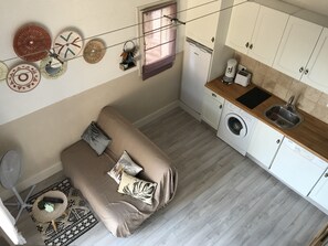 A compact living space with a sofa, a washing machine, and a kitchenette. - Cassiopeia quiet area  (Agde)