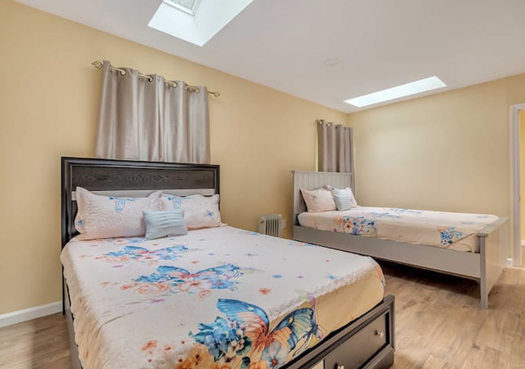 A bedroom with two beds, a skylight, and a radiator.