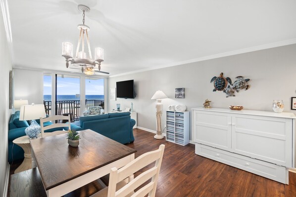 A spacious living room with a wooden dining table, a blue sofa, and a white cabinet.