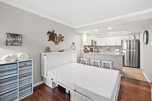 A compact bedroom with a bed, a small kitchenette, and a storage unit with drawers.