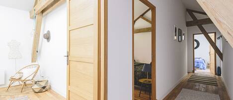 A room with a wooden door, a small seating area with a table and chairs, and a view of another room through an open door.