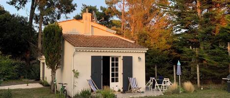 Une petite maison avec une piscine, deux chaises longues et un vélo.