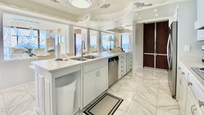 A spacious kitchen with a large island, modern appliances, and a view to the outside.