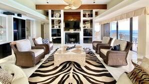 A spacious living room with a large zebra-patterned rug, two wicker sofas, a coffee table, and a fireplace.