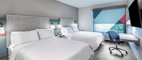 Habitación de hotel con dos camas, un escritorio, una silla y un televisor.
