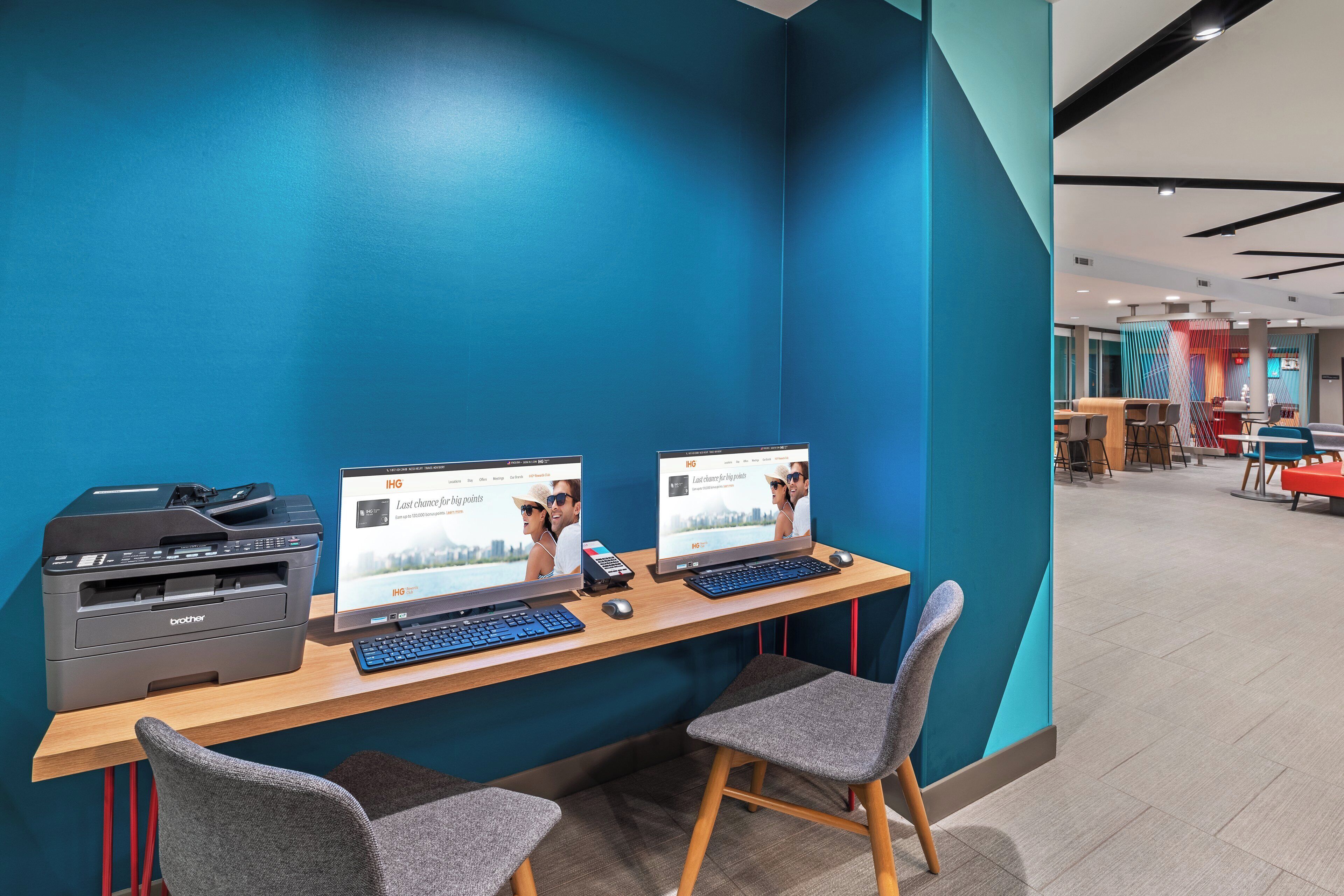 A workspace with two computer monitors, a printer, and a keyboard on a wooden desk.