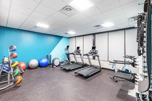 Un gimnasio con cintas de correr, balones de ejercicios y máquinas de pesas.
