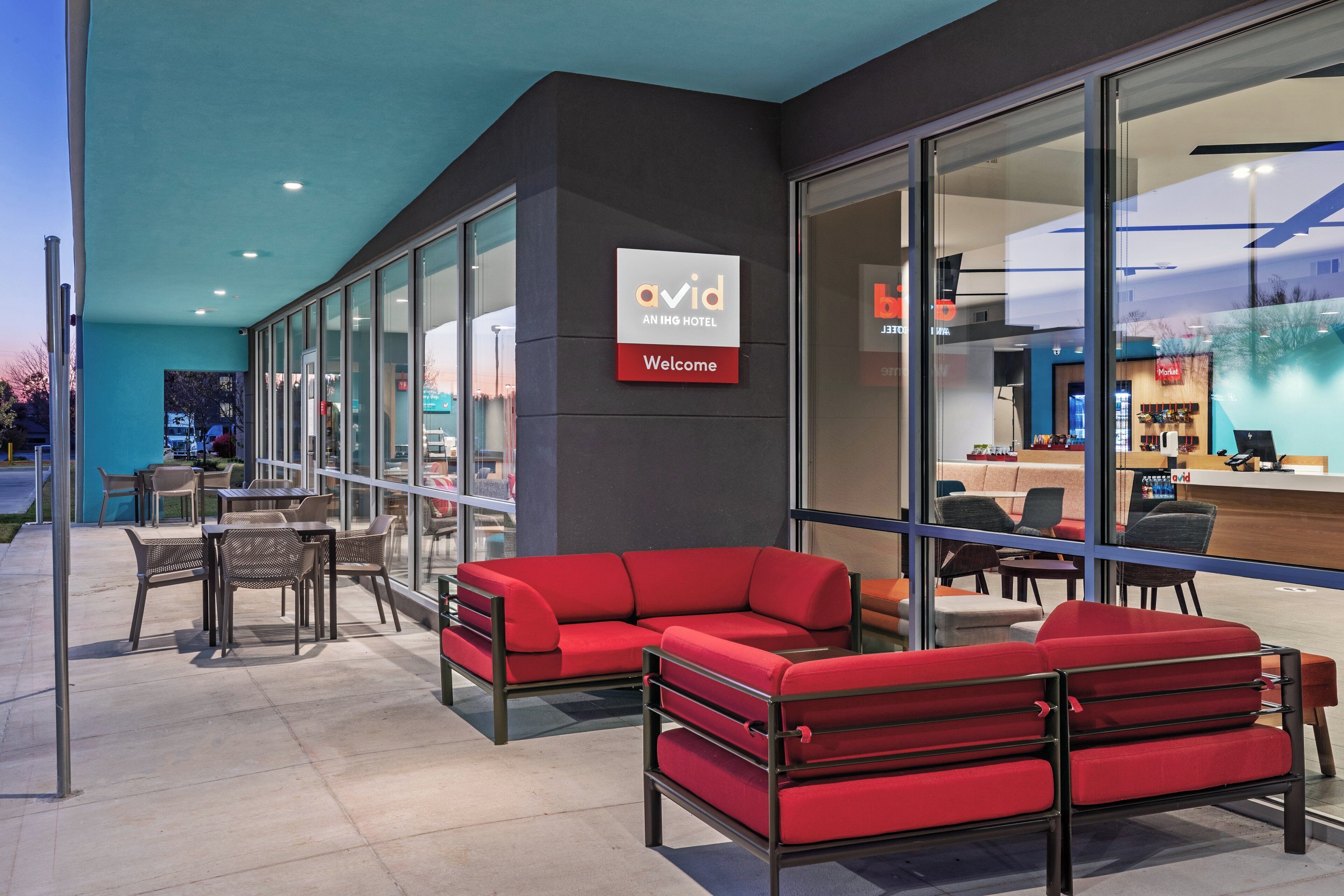 An indoor seating area with red sofas and tables, a reception desk, and a glass wall with a view.
