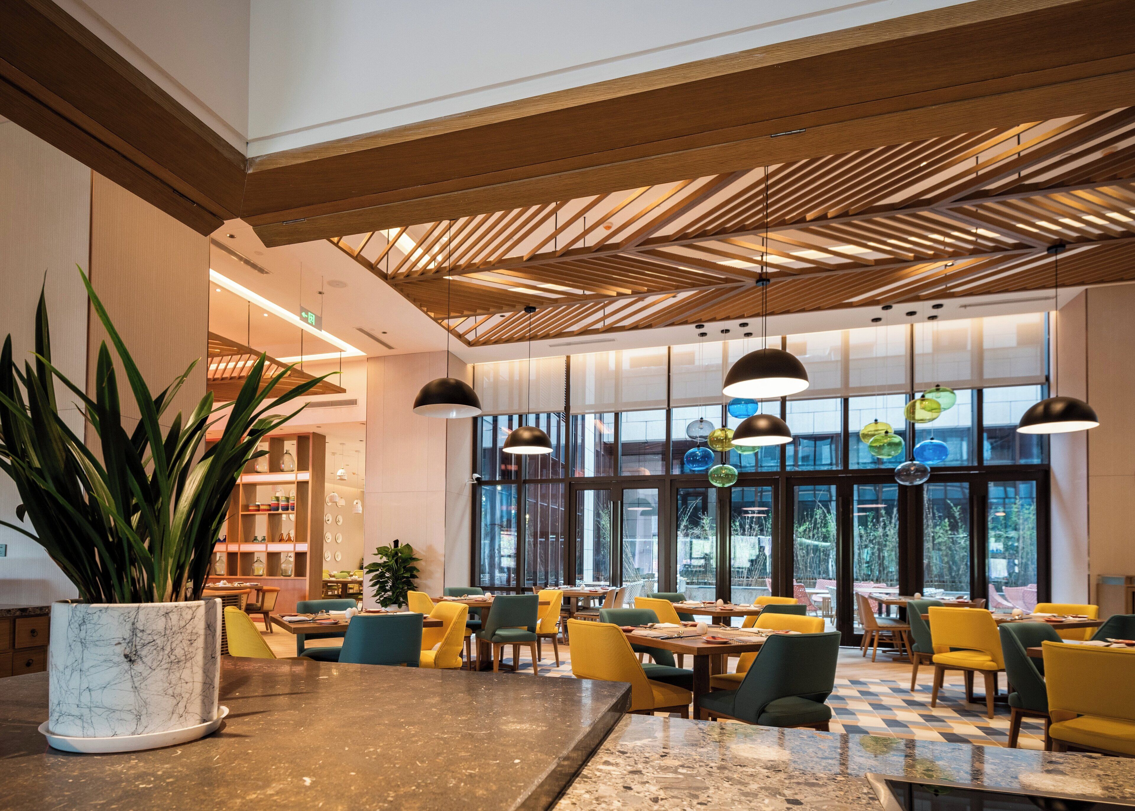 A modern interior with a checkered floor, wooden ceiling beams, and a variety of seating arrangements.
