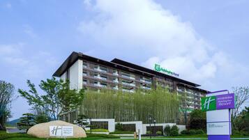 A Holiday Inn Resort building with a modern design, featuring a large signboard and a well-maintained lawn area.
