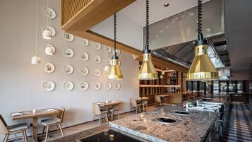 A modern restaurant interior with a bar area, wooden ceiling, and wall-mounted plates.