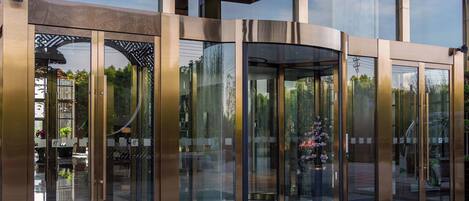 A modern building with a revolving door entrance, large glass windows, and a metal facade.