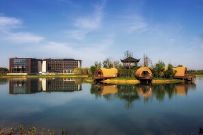 A modern hotel with a reflection in the water, surrounded by nature. - Holiday Inn Resort Maoshan Hot-Spring by IHG (Zhenjiang)