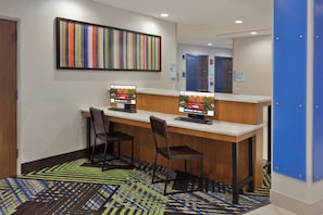 A reception desk with two computer monitors, a wooden counter, and two chairs. - Holiday Inn Express & Suites Fayetteville by IHG (Fayetteville)