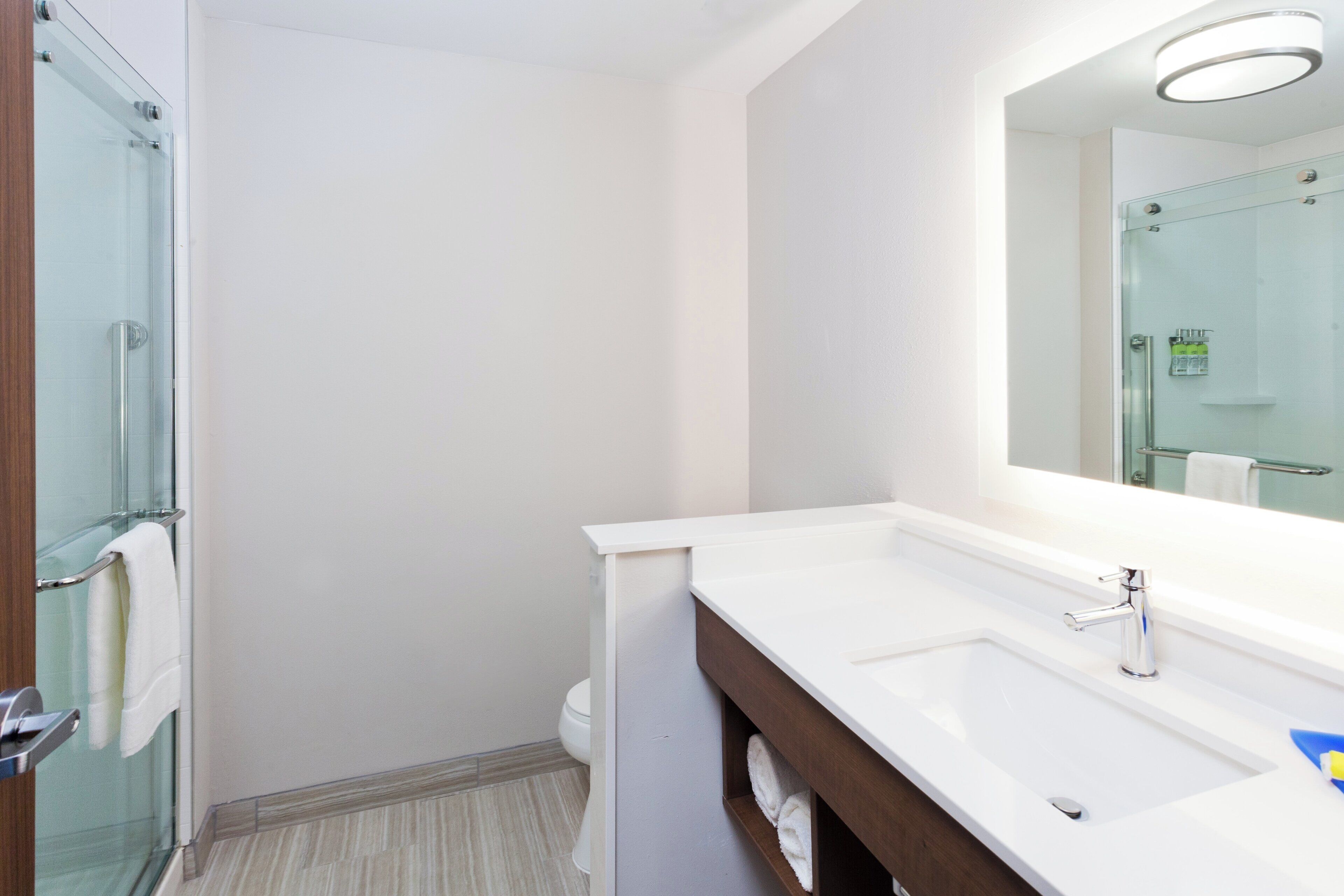 Une salle de bain moderne avec une douche à parois de verre, un lavabo blanc avec un miroir et des toilettes.