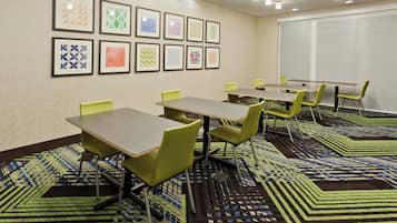 A conference room with tables and chairs, patterned carpet, and framed artwork on the wall.