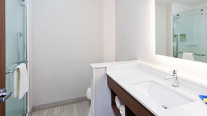 A modern bathroom with a glass shower enclosure, a white sink with a mirror above it, and a wooden vanity. - Holiday Inn Express & Suites Fayetteville by IHG (Fayetteville)