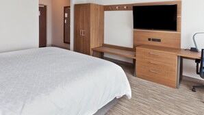 A hotel room with a large bed, a wooden desk with a flat-screen TV, a wardrobe, and a desk lamp. - Holiday Inn Express & Suites Fayetteville by IHG (Fayetteville)
