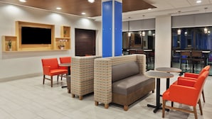 A modern interior with a sofa, chairs, and a TV mounted on the wall. - Holiday Inn Express & Suites Fayetteville by IHG (Fayetteville)