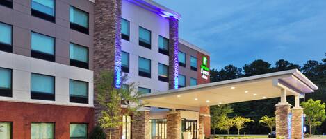 A hotel with a covered entrance, a parking lot with handicapped parking, and a sign indicating the hotel name.